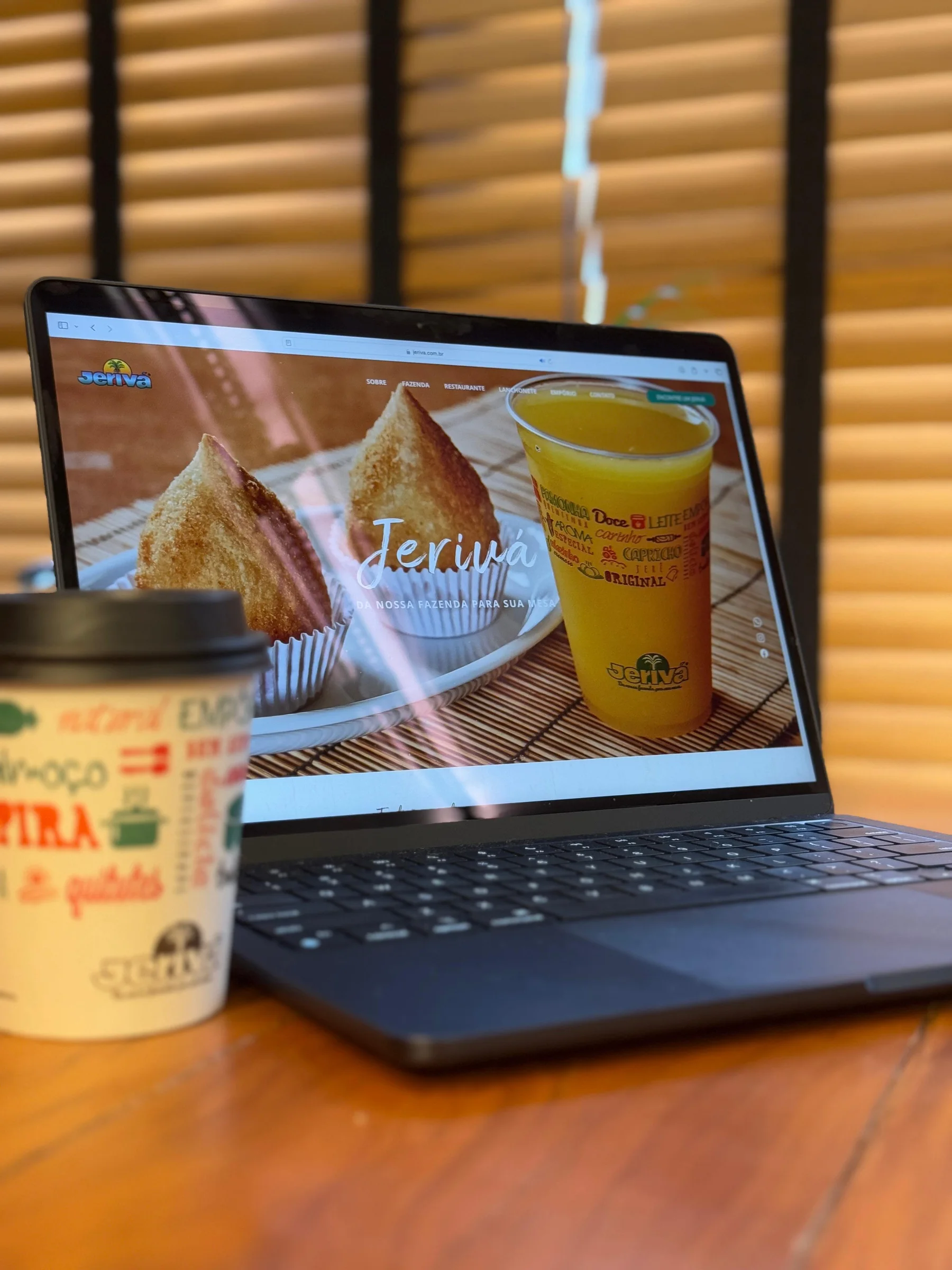 Site Jerivá em notebook, junto a um copo da marca